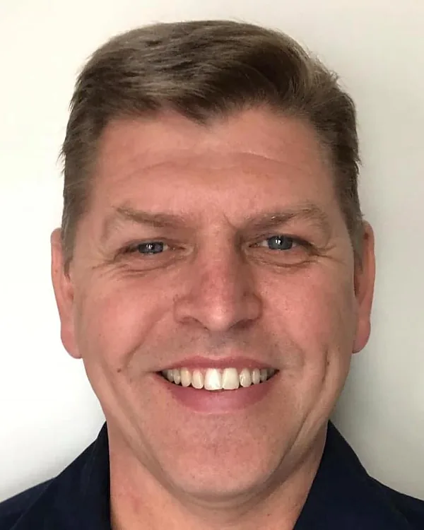 Neale Young, owner of Neale Young Plumbing Drainage, smiling in a navy work shirt